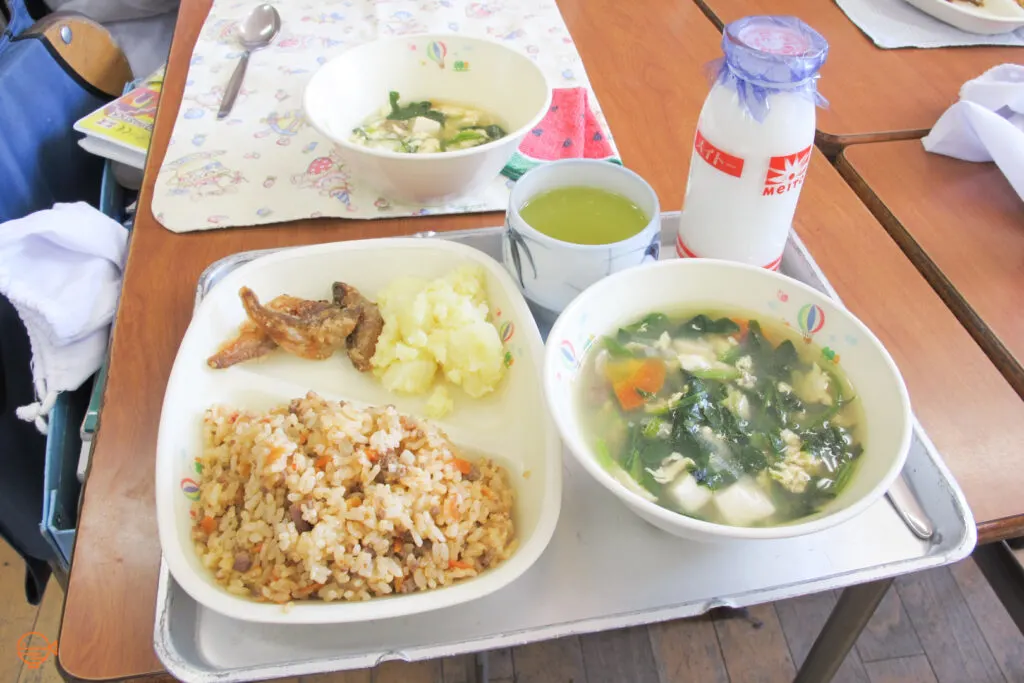 Tomato rice with fried fish and potato, a bowl of vegetable, seaweed and tofu soup, plus hot green tea and cold milk.