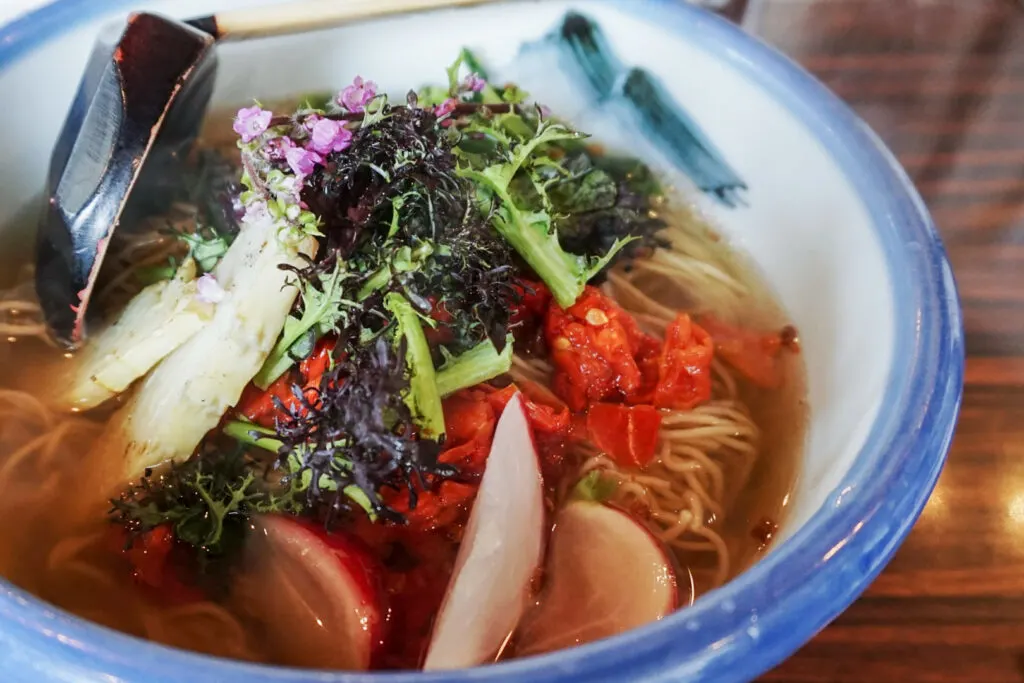 A colorful bowl of vegan ramen, the broth made of dried tomato, onions, carrots, celery and mushrooms. Photo by author, Kaori S.
