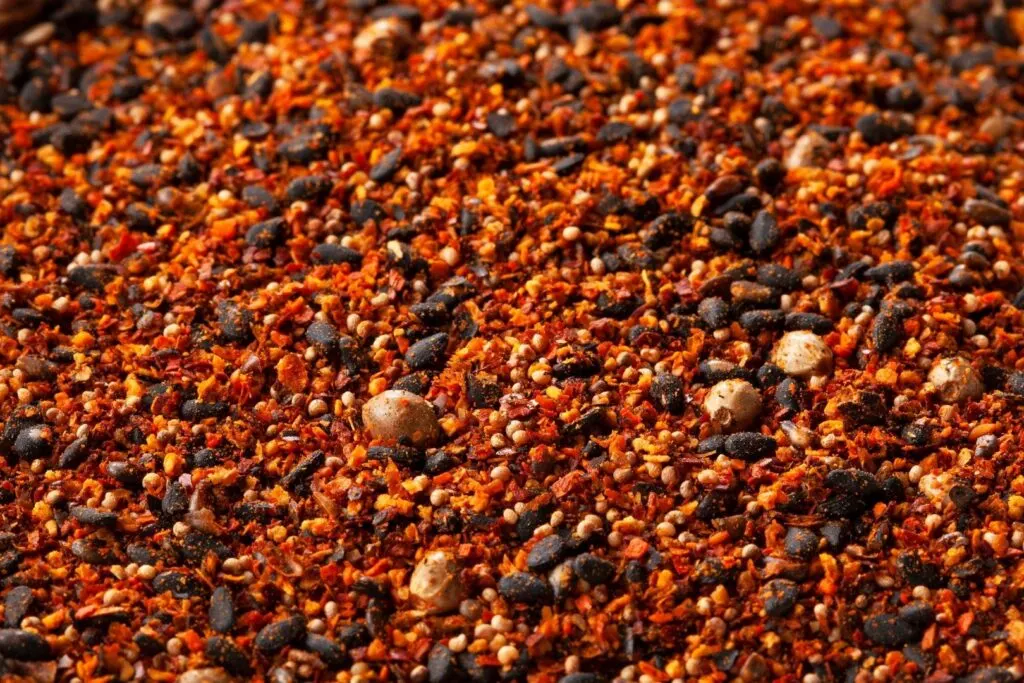 A close-up of the fiery red-orange color of this Japanese 7 spice mix and the various seeds and other ingredients added, showing that this is less of a powder and more of a substantive, course mix. 