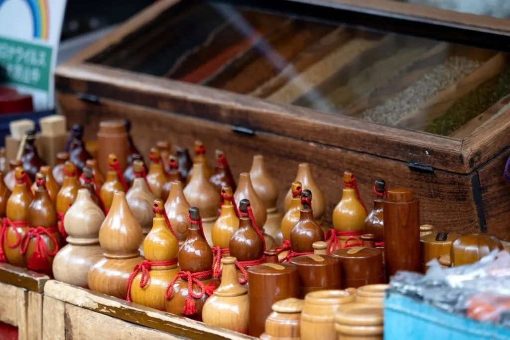 A stall selling various wooden containers used to store this Japanese spicy condiment. A large wooden case with a glass top sits behind the containers with seven different spices.