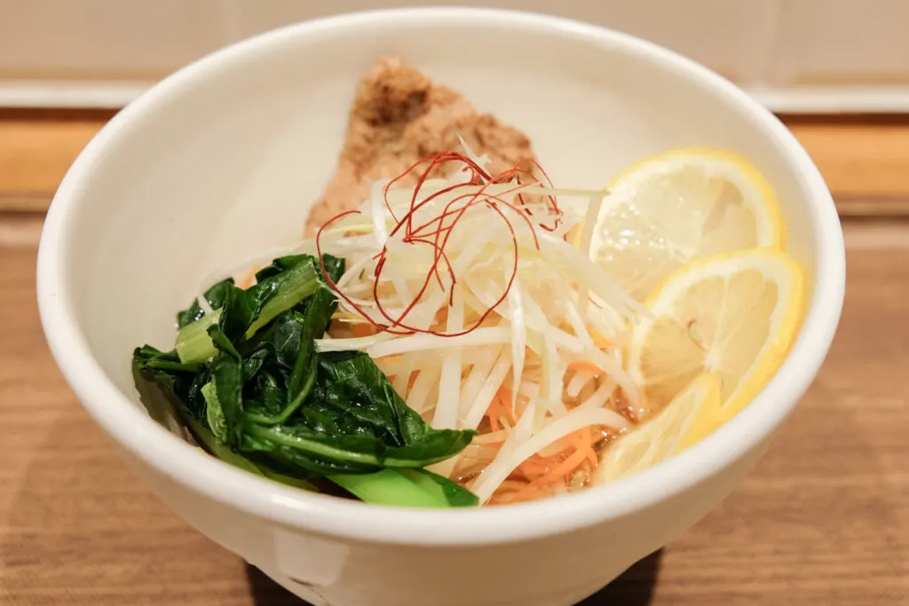 A bowl of T's Tan Tan 'Lemon Vegan Ramen' from their seasonal summer menu. With plenty of lemon slices and vegetables, it appears this Tokyo vegan ramen has virtually no soup.