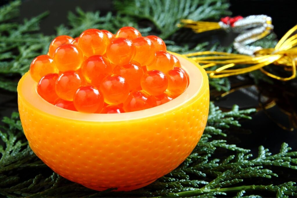 Pickled salmon eggs piled up inside half a plastic satsuma orange and surrounded by New Year decorations.