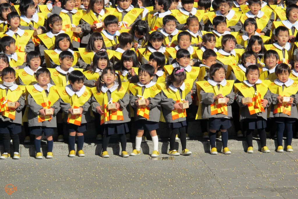 Kindergarteners on the steps of Sensoji Temple, Tokyo. Roasted soy beans can be seen scattered all over the ground in front of them after having thrown them at the "demon" during a mamemaki event. 