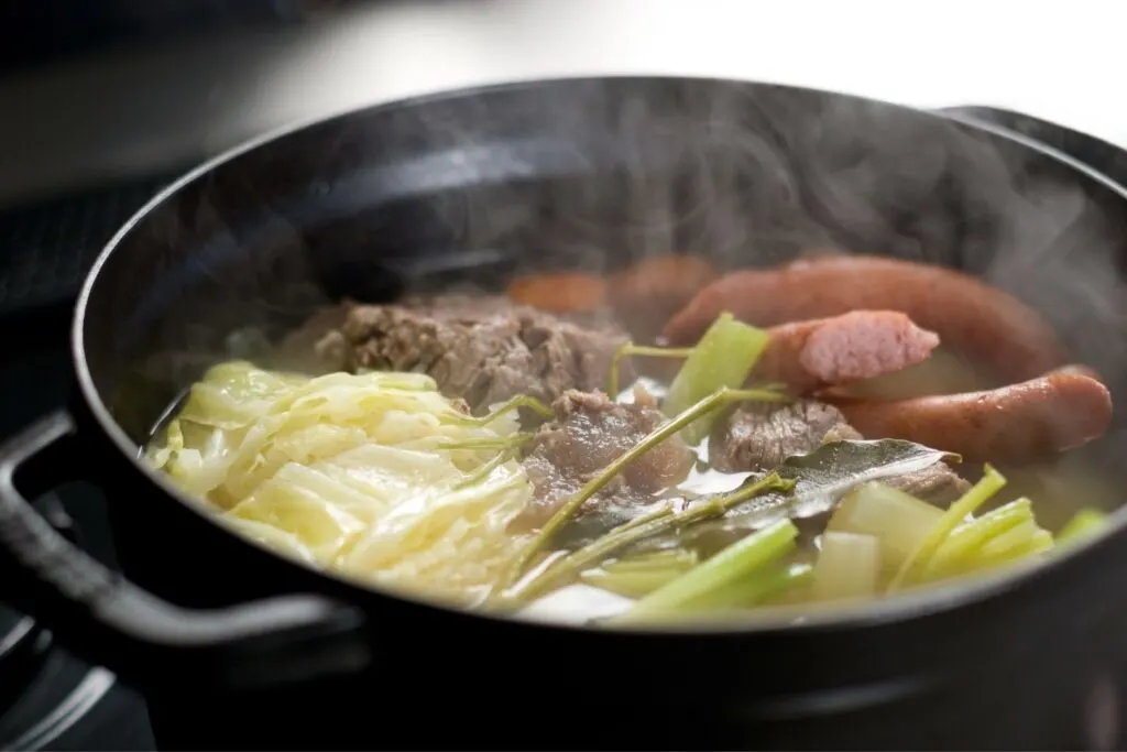 Surprising Japanese Food Names: A hearty bowl of "potofu" from the French "pot-au-feu". Inside the black pot, beef, sausage, cabbage and other vegetables in a broth can be seen with steam rising up.