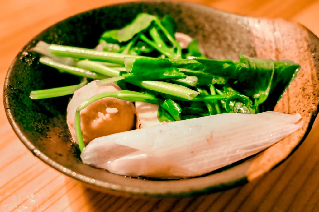 Sendai food: The local leafy green known as 'seri' sits in a wooden bowl on a wooden surface along with other nabe hot pot ingredients.