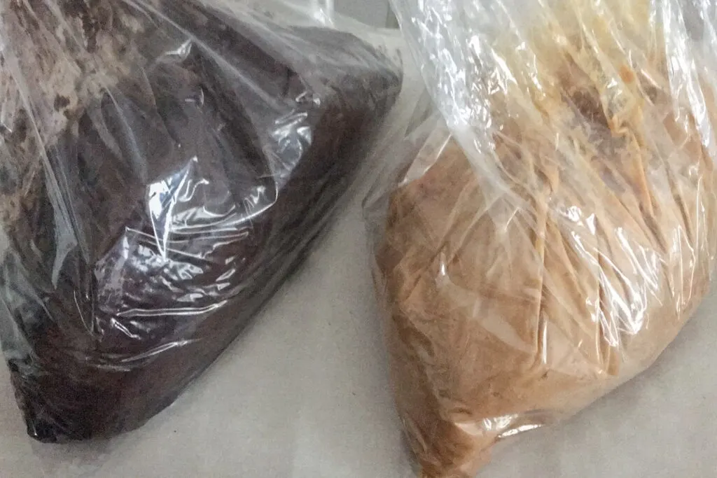 Two clear plastic bags of aged nerikasu. The one on the left is dark brown and has been matured for 5 years. The one on the left is light brown and has been aged for 3 years.