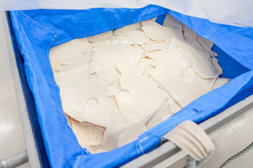 A large container with blue plastic lining filled with itakasu sheets - pieces of sake kasu that have been peeled off the filters in the sake press.