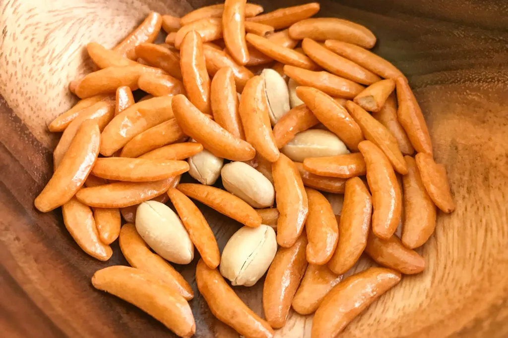 Popular Japanese snacks: A wooden bowl filled with kaki no tane - a mix of small crescent moon-shaped rice crackers and peanuts.