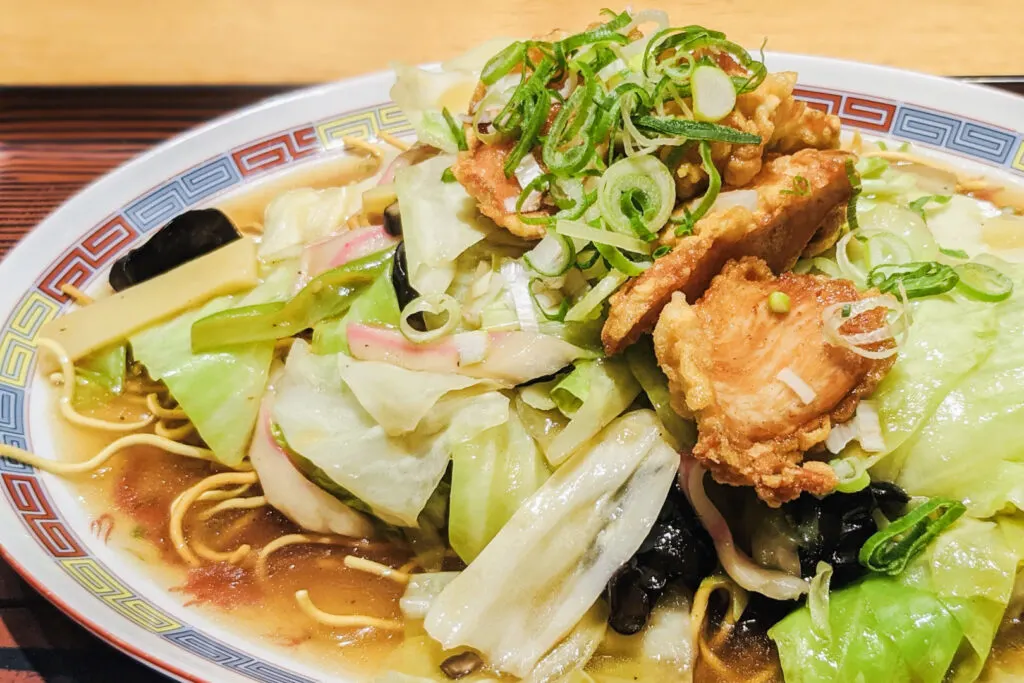 Yamaguchi food: A plate of Bari Soba in a chicken-based broth and topped with cabbage and other veggies (plus some deep-fried chicken or seafood and green onions on top).