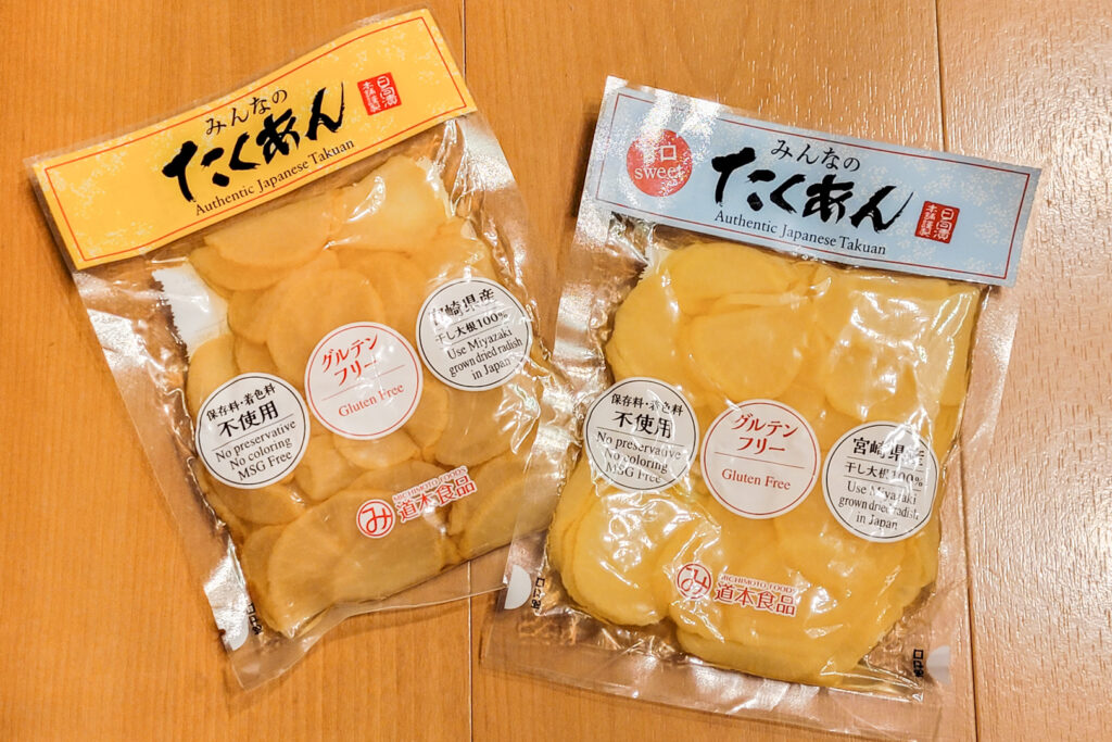 Two plastic packets of Michimoto Foods' gluten free takuan. They essentially look identical in the packaging (round yellow slices), but the one on the right is a sweet version.