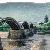 One of Yamaguchi's biggest claims to fame, its Kintaikyo Bridge, a five-arched wooden pedestrian bridge with a stone base. The bridge crosses the Nishiki River and green mountains can be seen in the background.