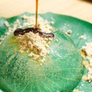 Yamanashi food: A close-up of a rounded 'Shingen Mochi' sweet on a green plate that makes the clear and wobbly, jello-like treat appear green also. Additionally, the 