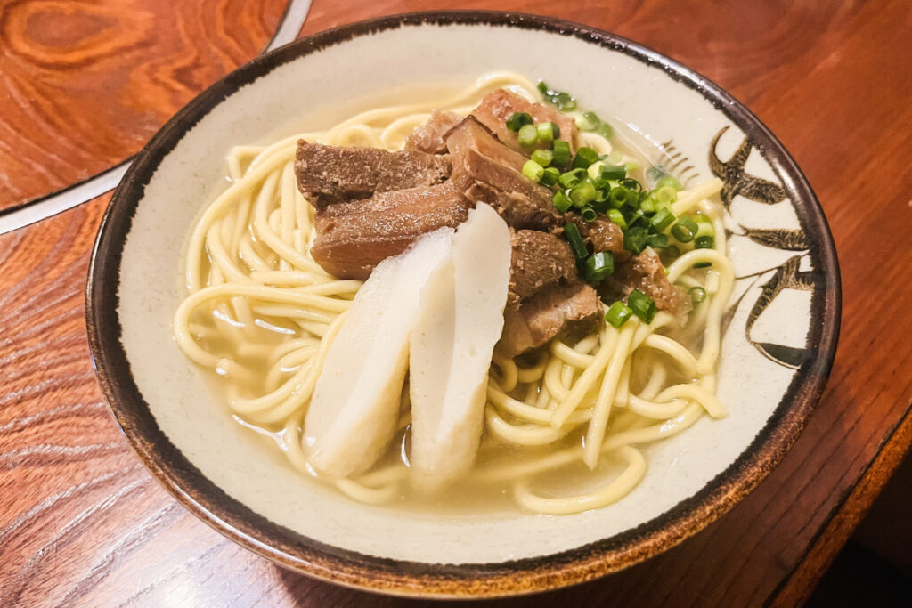 Okinawa food: A bowl of Yaeyama Soba noodles topped with pork, fish cake and green onions.